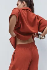 Pantalón marrón de tiro alto con cintura elástica, bolsillos delanteros y pernera ancha.