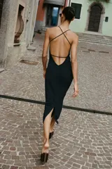 Vestido midi negro de punto con escote pico, tirantes finos cruzados en la espalda, aplique dorado y abertura en la cintura.