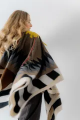 Ruana de tejido de punto con diseño geométrico en tonos beige, marrón, rojo y negro.