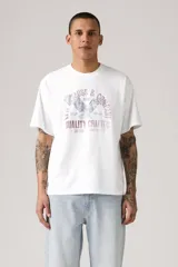 Remera blanca de corte holgado con estampado de águila y texto en tonos violeta y gris.