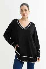 Sweater negro de tejido de punto con escote en V y ribetes blancos en cuello, puños y ruedo.