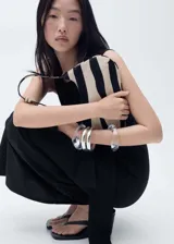 Vestido midi negro de algodón, sin mangas, con cuello redondo y detalle de nudo en la cintura.