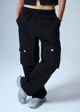 Pantalón cargo de denim negro, con cintura elástica y grandes bolsillos cargo a los lados con botones metálicos plateados.
