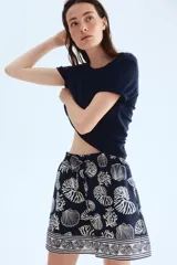 Short de tiro alto con estampado de motivos marinos en tonos azul y blanco. Presenta cintura elástica con cordón ajustable y bolsillos laterales.