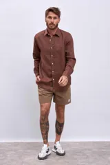 Camisa marrón de lino de manga larga con cuello clásico y cierre frontal con botones. Corte recto y calce regular.