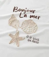 Remera de algodón blanco de corte regular, con cuello redondo y mangas cortas. Presenta un bordado frontal con motivos marinos como caracolas y una estrella de mar, acompañado de la frase "Bonjour La mer". Diseñada para la línea Curve & Plus Size.