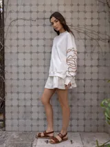 Buzo blanco de jogging sin friza, con cuello redondo y bordado floral marrón en las mangas.