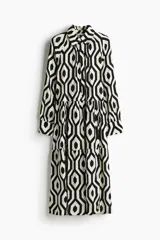 Vestido camisero midi de viscosa con estampado geométrico en blanco y negro. Tiene cuello camisero, tapeta de botones oculta, mangas largas raglán con puños sencillos y costuras fruncidas en la falda. Sin forrar.