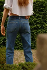 Jean de denim azul con corte slim regular, tiro medio, cinco bolsillos y cierre con cremallera y botón.