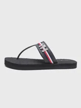 Sandalias de playa color azul marino con tiras de dedo y una banda transversal decorada con las icónicas rayas globales de Tommy Hilfiger y un monograma metálico 'TH'. Cuentan con suela de goma plana y capellada sintética.