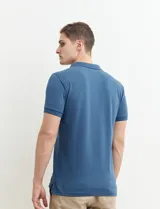 Chomba azul marino con pequeños lunares blancos, cuello clásico con botones y mangas cortas.