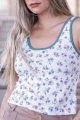 Musculosa de tela acanalada con estampado floral en tonos violeta y verde sobre base blanca. Presenta cuello redondo y sisas con ribete en color verde oscuro.