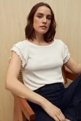 Top color rosado de tejido de punto acanalado, con cuello redondo y mangas cortas con volados.