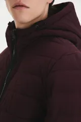 Campera puffer color bordó con capucha, cierre frontal con cremallera negra y bolsillos laterales con cierre.