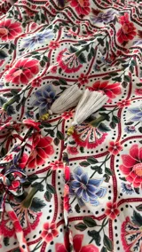 Vestido largo estampado con escote profundo en V y tirantes finos. El estampado presenta motivos florales en tonos terracota, azul apagado y crema, dispuestos en un patrón repetitivo con franjas decorativas.