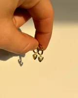 Par de aros tipo huggies dorados con dije colgante de corazón calado.