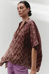 Blusa marrón con estampado abstracto, cuello camisero y botones en la parte delantera.