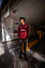 Buzo de algodón color bordó, estilo universitario, con cierre medio frontal y cuello alto. Estampado frontal con el texto "Since 19" y un ancla con laureles en amarillo y blanco.