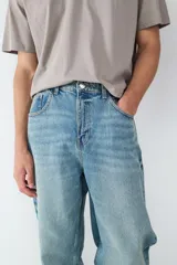 Pantalón de jean celeste de corte recto y holgado, con diseño clásico de cinco bolsillos, cierre de botón y cremallera.