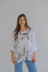 Blusa blanca de lino con estampado abstracto en tonos marrones y grises, de corte holgado y mangas 3/4 con puños abotonados.