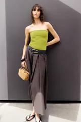 Falda midi color blanco hueso, de tiro alto y corte evasé. Incluye cinturón negro con hebilla metálica.