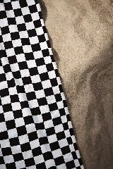 Toalla de playa con estampado de damero (cuadros) en blanco y negro, que se transforma en un bolso de mano con asas cortas.