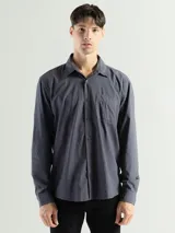 Camisa de manga larga color gris oscuro, confeccionada en algodón, con cuello clásico, cierre frontal con botones, bolsillo de parche en el pecho y corte clásico.