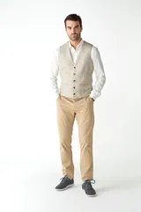 Chaleco de vestir para hombre, color marrón claro con textura tweed. Diseño sastrero con cuello en V, cierre frontal con botones, bolsillos ribeteados y forro interno. Confeccionado en lana fina sin teñir, diseñado exclusivamente por Don Baez.