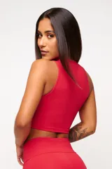 Top deportivo blanco de corte cropped, con cuello alto y logo estampado en el frente.