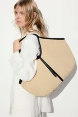 Bolso shopper de paja de plástico trenzada color beige con detalles en tejido revestido negro. Asas estrechas, correa fina en la parte superior y bolsillo interior con cierre.