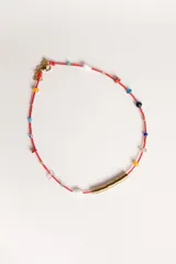 Gargantilla de hilo rojo con cuentas de colores y dije central de cilindro dorado.