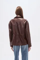 Chaqueta marrón de eco-cuero con textura de cocodrilo, cuello solapa, bolsillos con tapa en el pecho y frunces ajustables en la cintura mediante cordones.