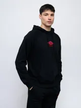 Canguro negro de felpa sin frisa con capucha y logo Umbro bordado en rojo en el pecho. Cuenta con bolsillo tipo canguro y cordones ajustables en la capucha.