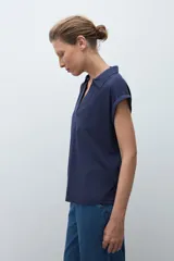 Remera de manga corta color rosa pálido, con cuello polo y escote en V con detalle de bordado en el borde.