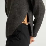 Sweater gris oscuro de punto tricotado con cuello redondo y mangas largas. Tiene aberturas laterales con cadena dorada.