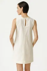 Vestido mini color crema, sin mangas, de lino y viscosa, con cuello en V y volados en el escote.