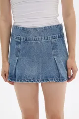 Minifalda de jean azul con cintura ancha y pliegues frontales.