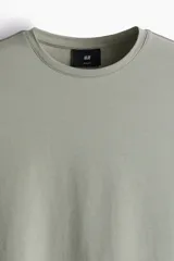 Remera verde oliva de algodón liviano, corte ajustado, cuello redondo ribeteado y bajo recto.