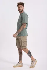 Remera de algodón color verde salvia, con cuello redondo y manga corta. Presenta un pequeño parche estampado en el pecho con un diseño gráfico.