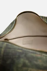 Bolso de hombro tipo bandolera con estampado de parches de denim en tonos verdes, marrones y azules. Tiene un compartimento principal con cierre de cremallera, un bolsillo interior con cremallera y un bolsillo trasero con cremallera. El asa de hombro es ajustable.