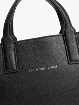 Cartera tote negra con textura granulada, doble asa corta y correa larga de tela con logo de la marca en blanco y negro.