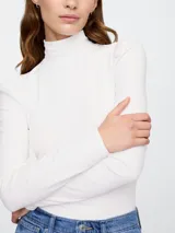 Remera blanca de cuello alto con mangas largas abullonadas en los hombros.
