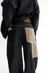 Pantalón de jean negro de corte acampanado, con parches de pana color visón y cordones en la cintura.