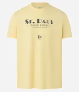 Remera amarilla de algodón, corte recto, con cuello redondo y mangas cortas. Estampa frontal con el texto "St. Paul Grand Hotel" y un logo pequeño.