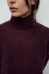 Jersey de punto color gris oscuro, de cuello alto y manga larga con terminaciones en rib.
