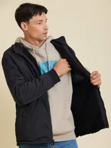 Campera gris oscuro de poliéster con textura tipo sherpa, cuello alto, cierre frontal con cremallera, bolsillos tipo parche en el pecho y puños elásticos.