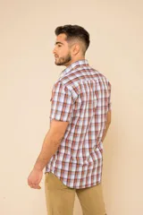 Camisa de manga corta con estampado a cuadros en tonos azul, rojo y blanco. Cierre con botones y tela ligera.