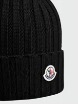 Gorro de lana tejido a punto acanalado, color bordó, con parche circular del logo de Moncler en el frente.