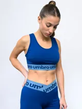 Top deportivo azul eléctrico, tipo crop top, con escote redondo y tirantes anchos. La banda elástica inferior es de color azul claro con el logo de Umbro repetido en azul oscuro.