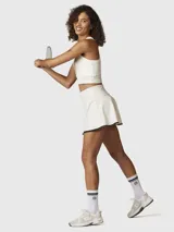 Falda skort blanca con borde negro en el dobladillo, confeccionada en tejido reciclado con tecnología Aircool. Incluye un short integrado con bolsillo.